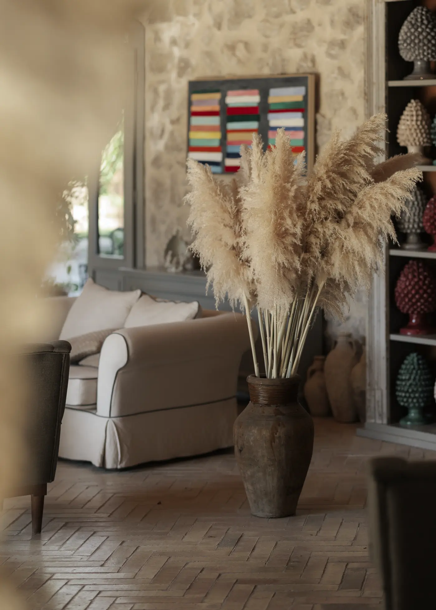 Salotto della Masseria con pareti in pietra, pampas e pigne in ceramica siciliana